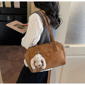 Detail of vintage brown tote bag with decorative front pocket and plush rabbit charm