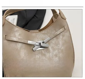 Detailed view of beige glossy leather bucket bag featuring silver crisscross hardware lock