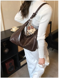 Détail du sac hobo en cuir marron foncé avec charme d'ours et fermeture éclair