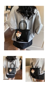 Detail of black lychee grain leather bucket bag with cute brown bear plush charm accessory