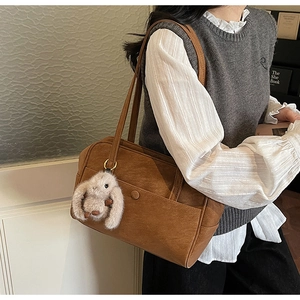 Detail of vintage brown leather tote bag with rabbit charm and dual slim shoulder straps