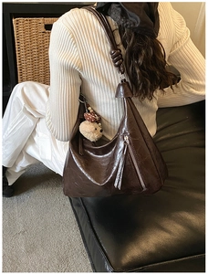 Détail du sac hobo en cuir huilé marron foncé avec fermetures à pompons et bijou d'ours