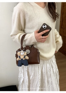 Dettaglio della borsa marrone con chiusura dorata e ciondolo a forma di orsetto