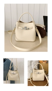 Detail of cream leather bucket bag with silver clasp, top handle and crossbody strap