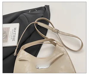 Detail of adjustable strap and silver metal hardware on beige bucket bag with grain texture