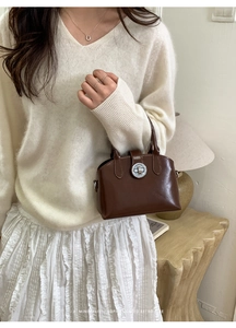 Close-up of a brown retro handbag featuring a polished silver twist-lock closure