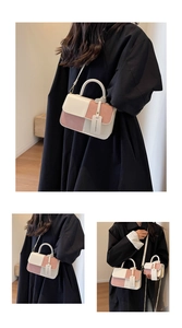 Detalle del bolso baguette bicolor rosa y crema con herrajes metálicos y etiqueta de logo