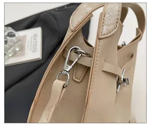 Detail view of silver metal buckle and stitching on a textured leather bucket bag