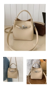 Detailed view of beige pebble grain leather bucket bag with metallic twist lock and handle