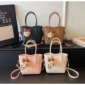 Detailed display of four leather bucket bags in black, brown, pink and white with teddy charms