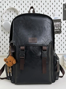 Minimalist black leather laptop backpack with buckle straps and a cute teddy bear charm