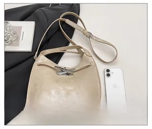 Detail of light beige hobo bag with pleated texture and adjustable strap on lifestyle setting