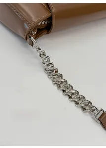 Detail of silver geometric chain and zipper on brown leather baguette shoulder bag