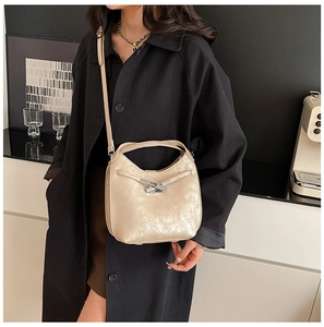 Détail du sac seau doré champagne avec cuir métallisé froissé et nœud argenté élégant
