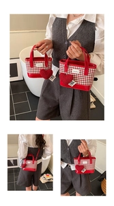 Détail du sac seau à carreaux rouges avec garniture en cuir et breloque coeur en peluche