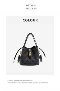 Detail view of black embossed bucket bag with golden twist lock and woven handle