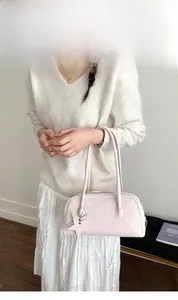 Close-up of light pink baguette bag featuring double handles and star-shaped charm detail