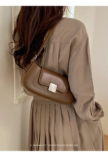 Minimalist brown retro baguette bag with metallic buckle shown on model shoulder
