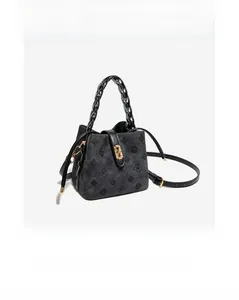 Detail of black embossed bucket bag featuring gold twist lock and woven chain handle