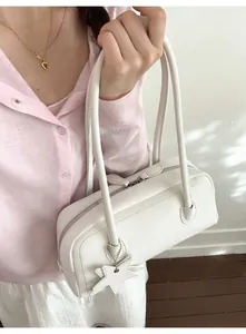 Close-up of a white minimalist shoulder bag featuring dual zippers and a star charm