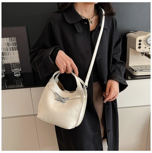 Détail du sac seau beige avec fermoir métallique en bambou sur manteau noir
