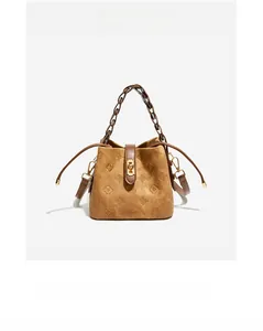 Close-up of embossed floral pattern on brown suede leather bucket bag with chain handle