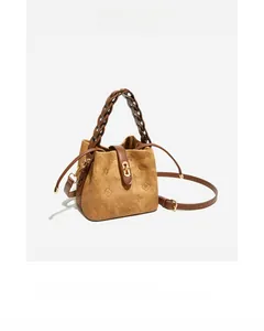 Detailed close-up of dark brown embossed bucket bag with woven handle and gold hardware