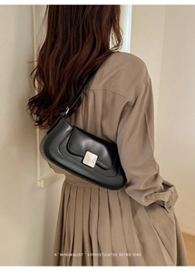 Rear view of model wearing a minimalist black leather underarm bag with silver buckle