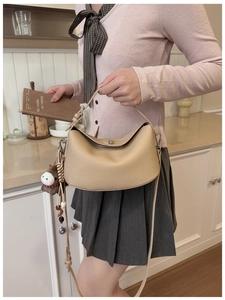 Lindy style beige lychee leather bag detail with brown horse pendant and model posing