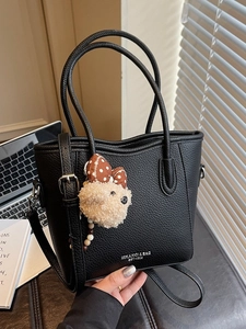 Black lychee leather tote bag with dog charm, featuring shoulder strap and top handles