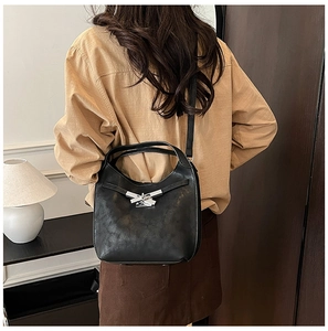 Detail of black leather bucket bag with silver irregular buckle and crossbody strap