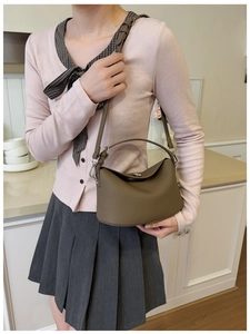 Detail of dark brown litchi grain leather texture and shiny silver metal buckles on handbag