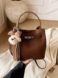 Secchiello in pelle marrone con chiusura argento e ciondolo a peluche in ambiente caldo