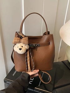 Elegante borsa a secchiello in pelle marrone con manico e ciondolo a forma di orsetto