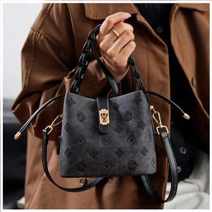 Detailed view of black bucket bag with embossed jacquard texture and gold metal clasp