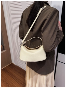 Detailed view of the creamy white lychee grain leather texture on this half-moon bag
