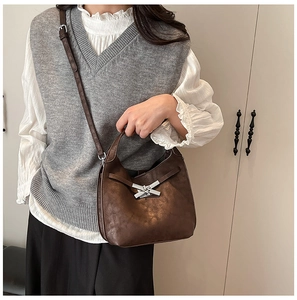 Détail d'un sac seau en cuir marron foncé avec une boucle de nœud en métal argenté