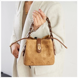 Detailed macro view of vintage embossed floral pattern and woven handle on brown bucket bag