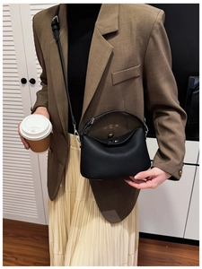 Close-up of black lychee grain leather underarm bag with silver turn-lock and shoulder strap