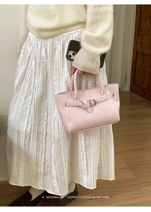 Detail of pink minimalist handbag with retro buckle and comfortable hand strap handle