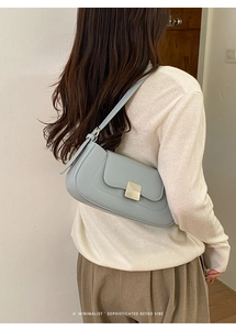 Detail of light blue faux leather underarm bag with gold metal buckle and retro vibe