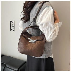 Détail du sac seau café foncé avec texture mate vintage et boucle argentée sur un modèle