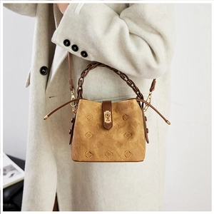 Detail of vintage embossed bucket bag featuring woven handle and metallic clasp closure