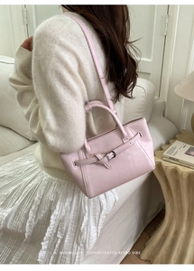 Close-up of a pink leather tote bag with decorative buckle strap and shoulder strap