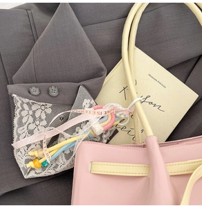 Detail of colorful woven rainbow charm with pearl chain and love ribbon on a stylish tote