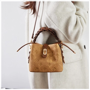 Close-up of vintage embossed bucket bag with woven handles and gold metal lock buckle