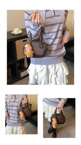 Detail of dark brown leather Boston bag featuring a cute yellow plush doll charm