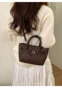 Deep brown retro trapezoid handbag with buckle detail styled in a minimalist home setting