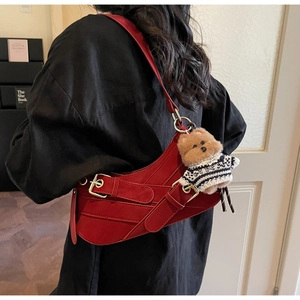 Detail of dark red leather saddle bag with bear charm worn by a model in black top