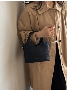 Sac à main noir chic à texture marbrée porté avec un trench-coat élégant et moderne